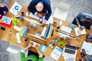 a group of people sitting around a wooden table.